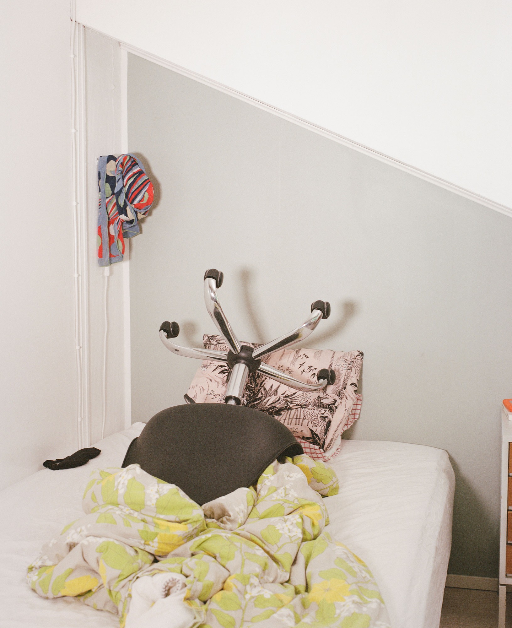 An office chair resting on an unmade bed