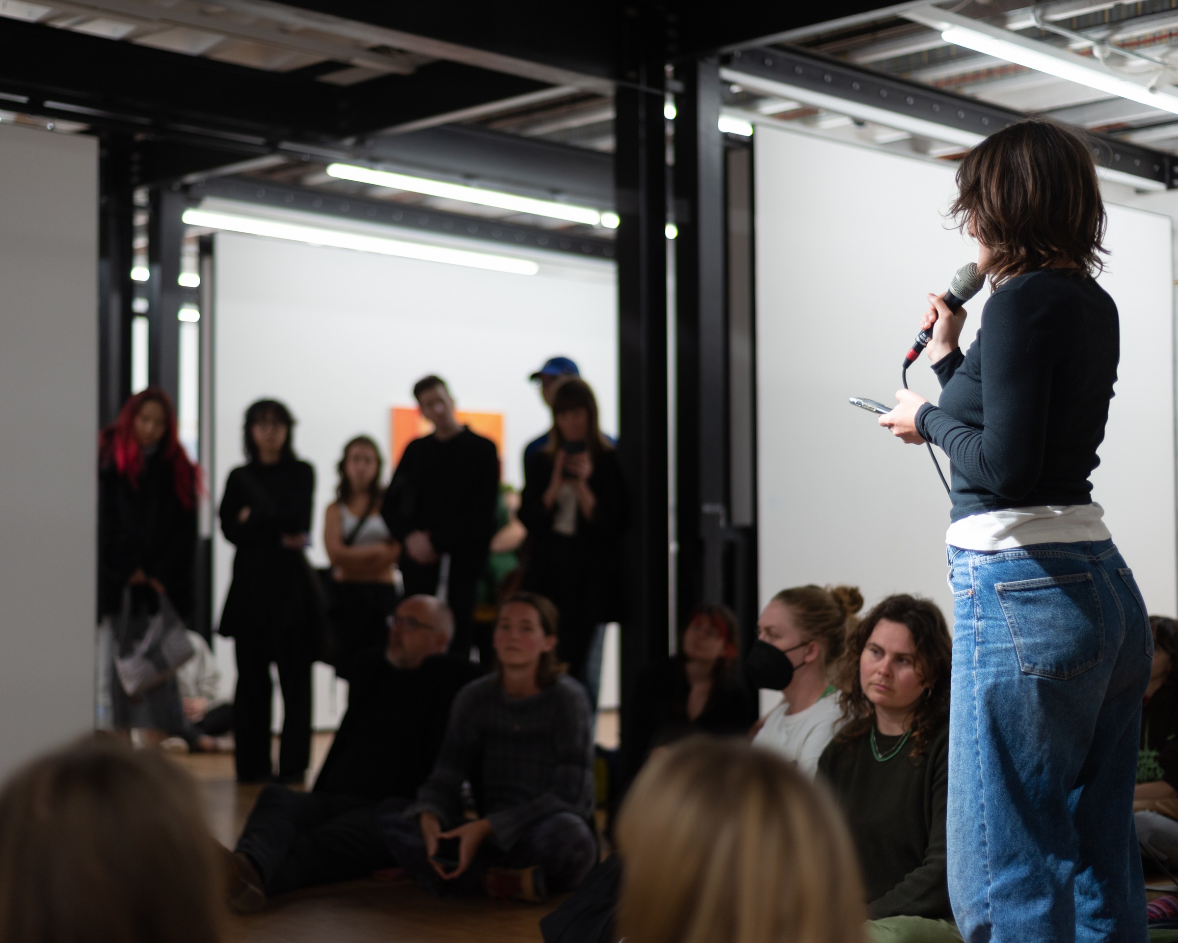 Auto Sun performance, artist speaking into a microphone to a seated audience