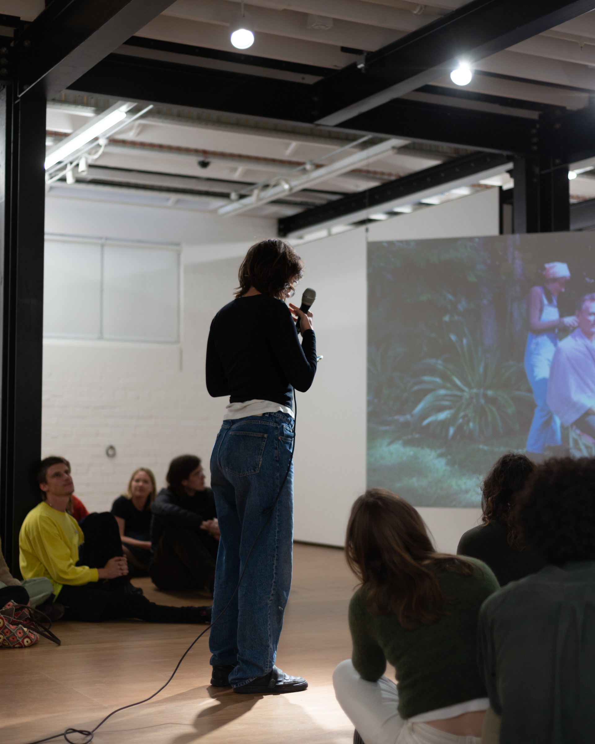 Auto Sun performance, artist speaking into a microphone before the projection