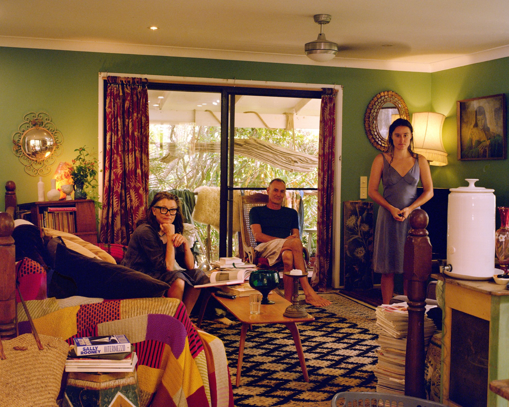 Portrait of a family, two seated and one standing, in a green living room