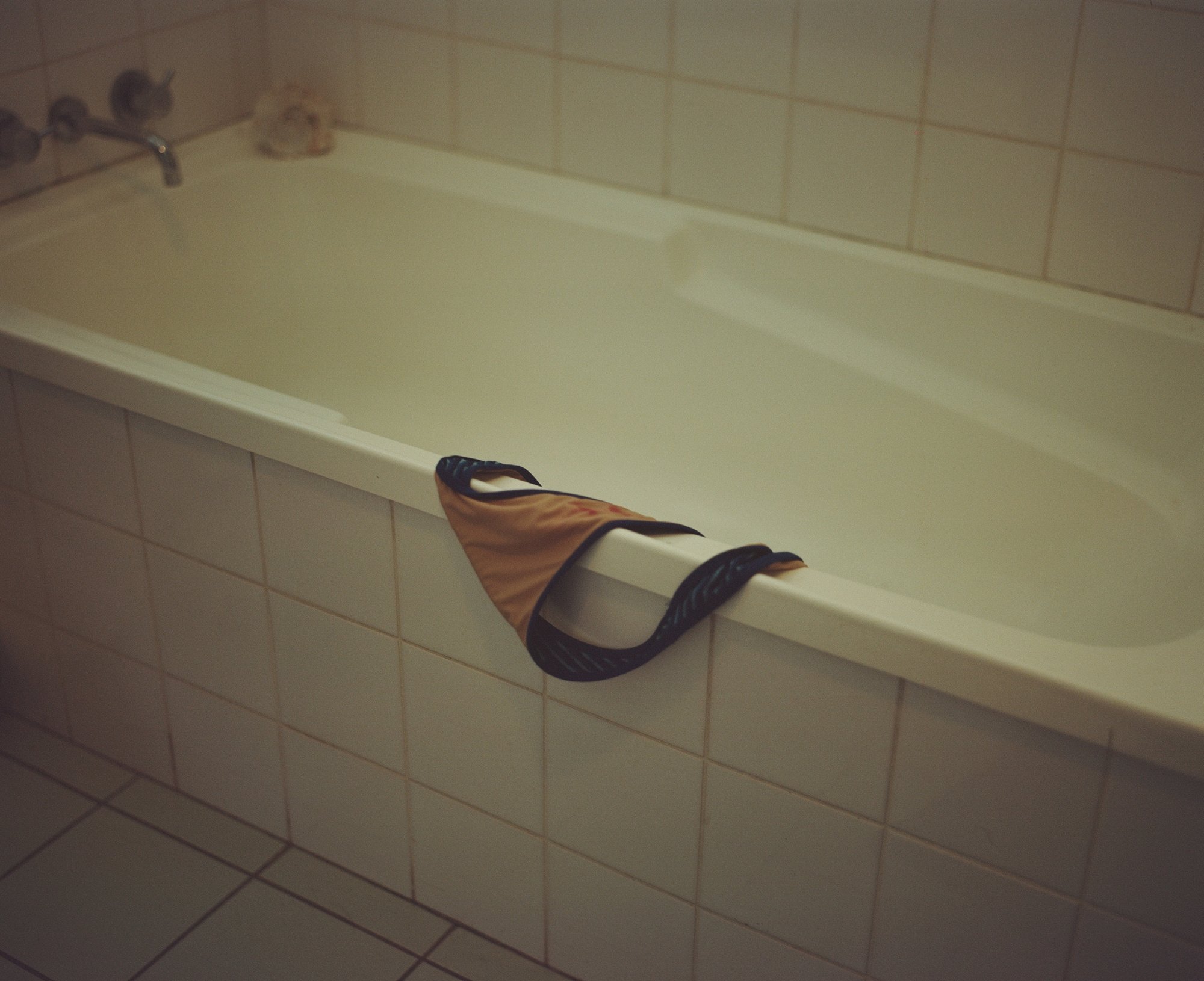 Bikini bottoms hanging over the edge of a bathtub