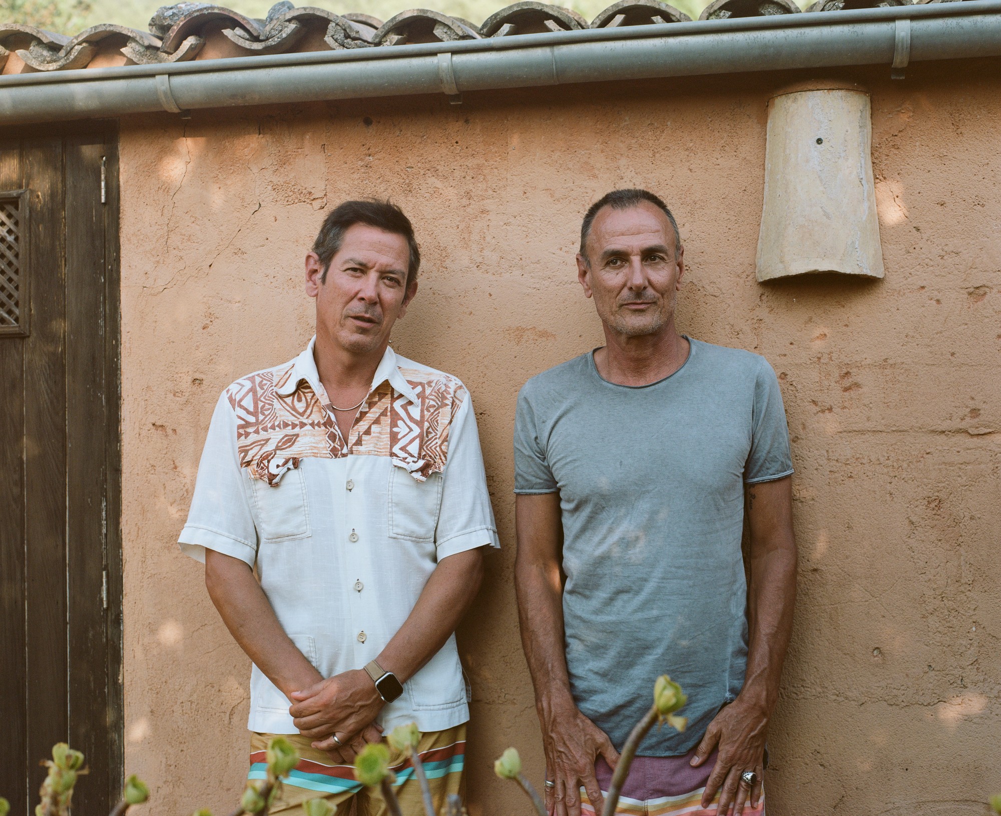 Portrait of two men against a stucco wall