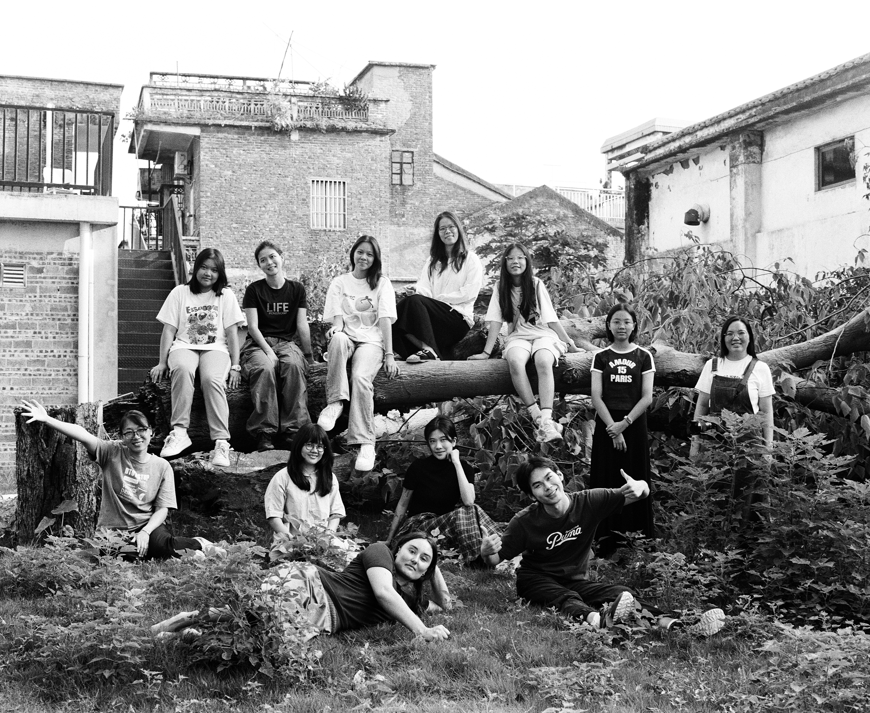 Group portrait of the Luohang residency cohort sitting and lying on a fallen tree trunk