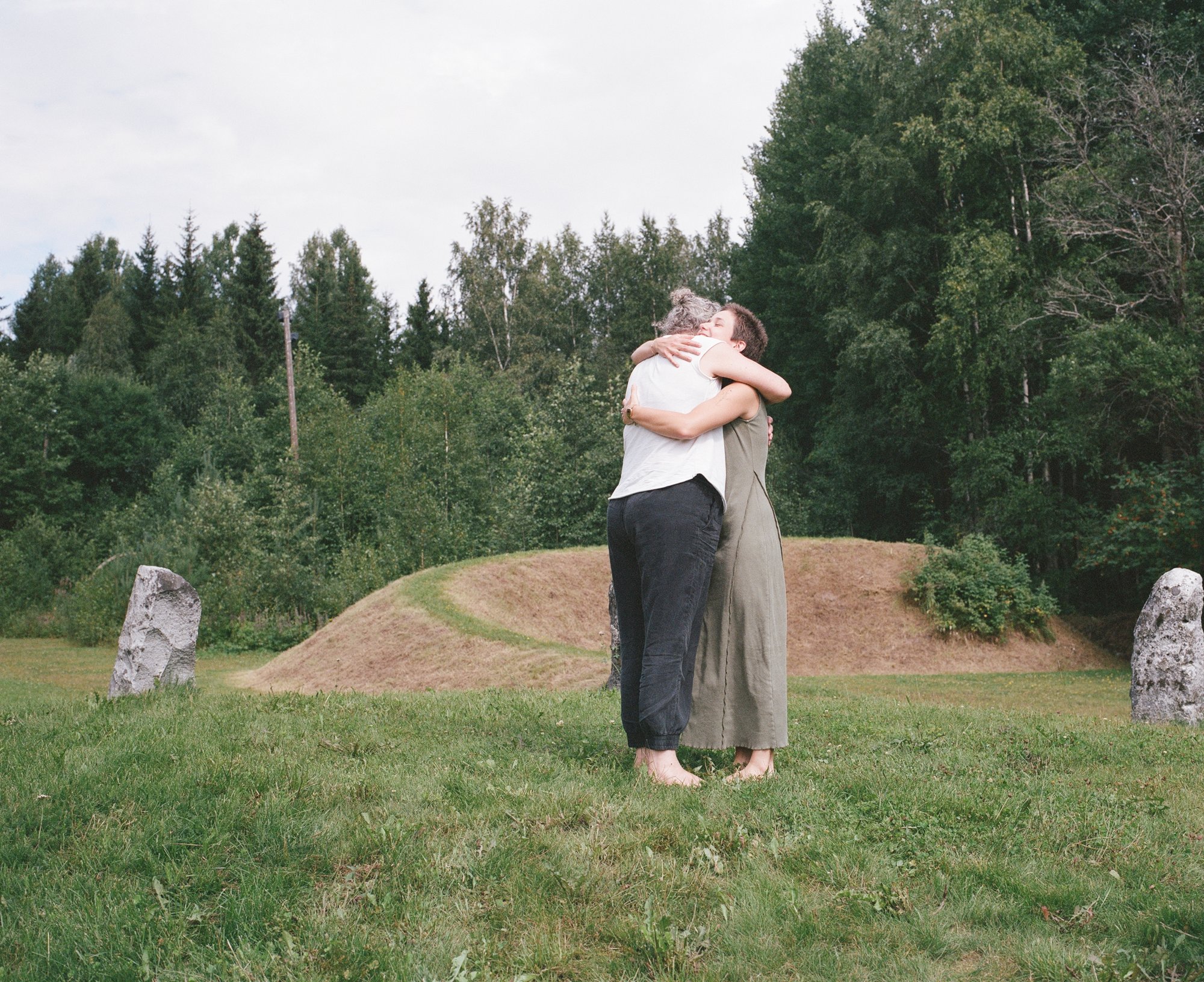 Two figures embracing among standing stones, seen from behind