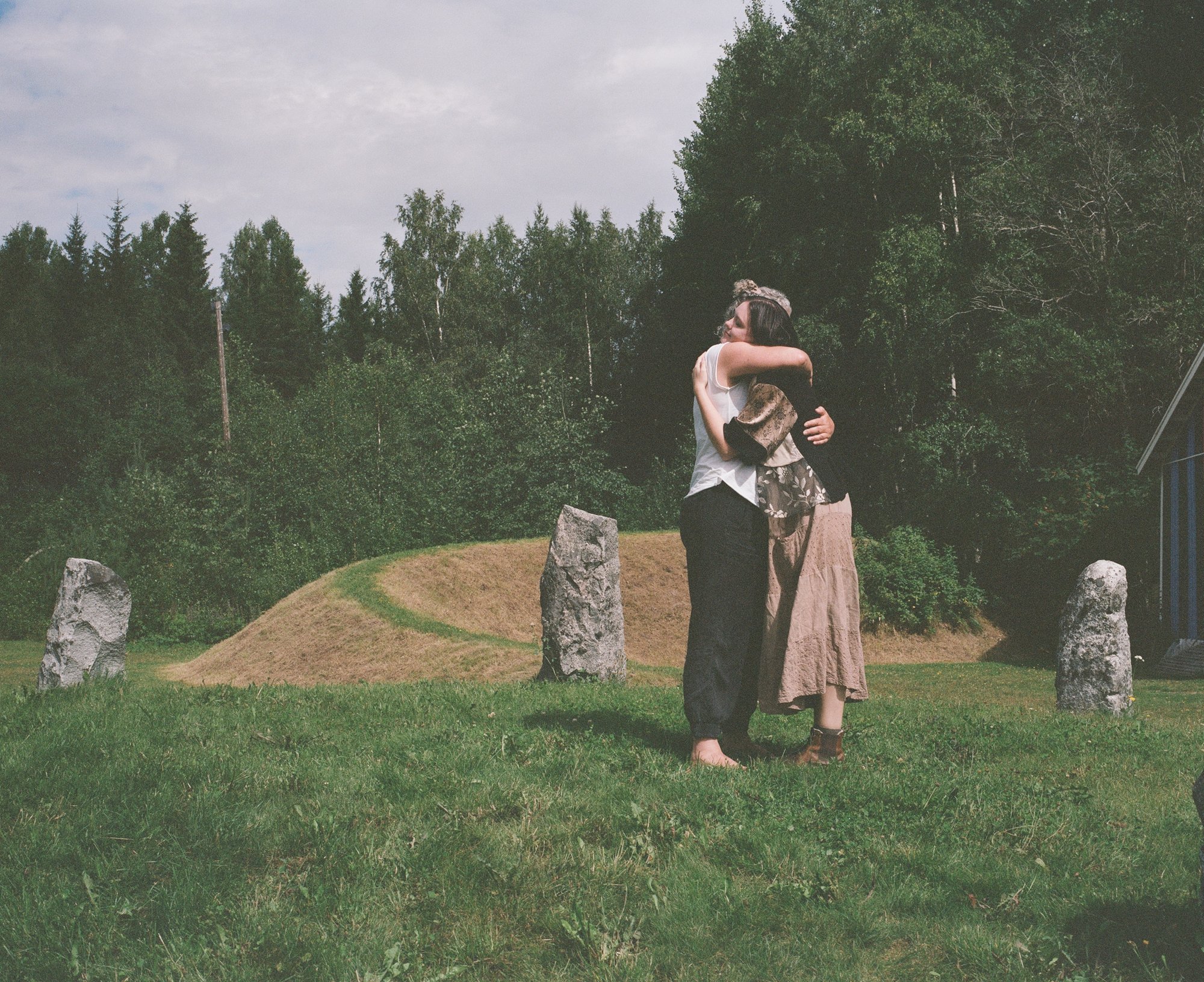 Two figures embracing among standing stones, one in a long patterned skirt