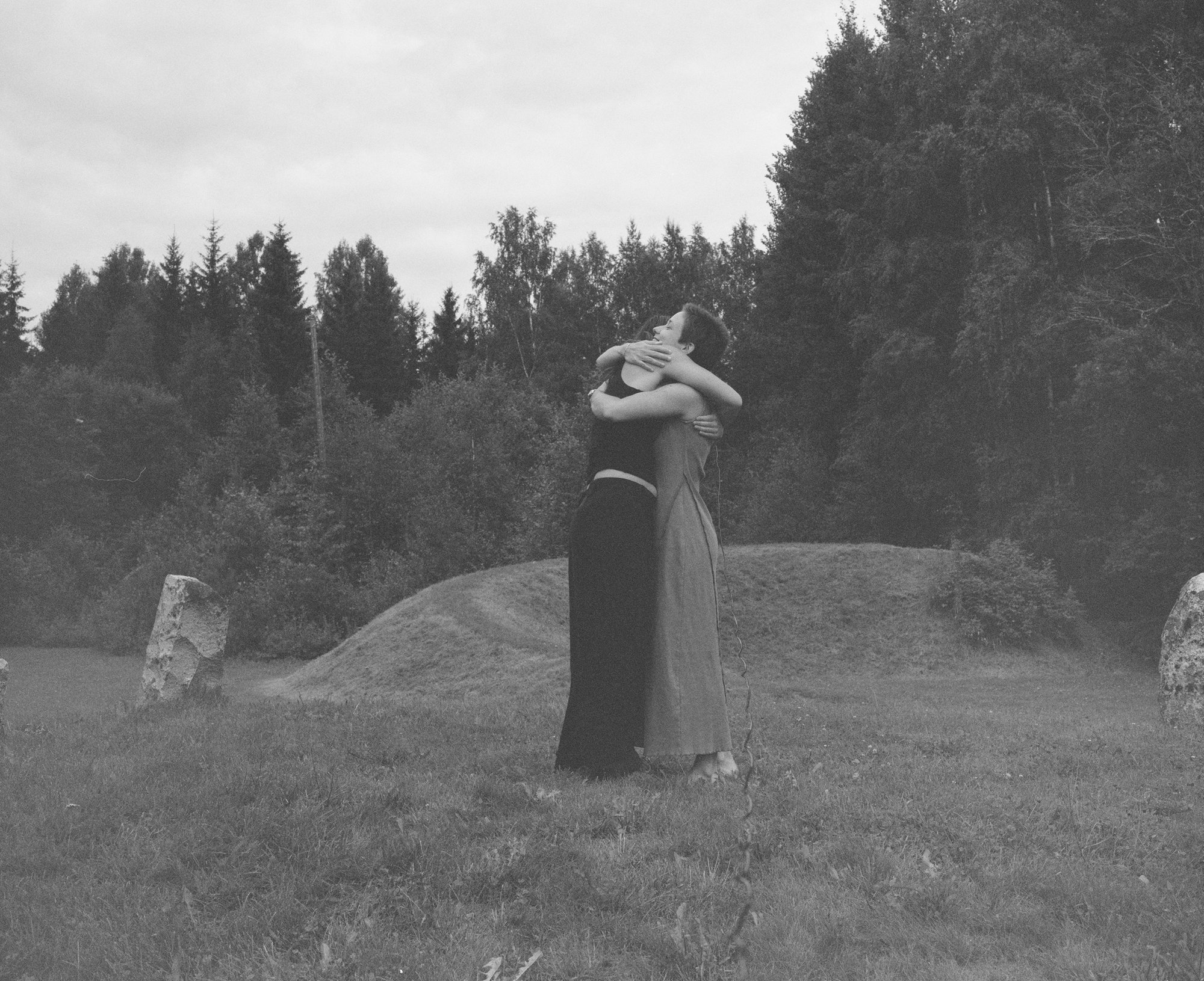 Black and white photograph of two figures embracing among standing stones