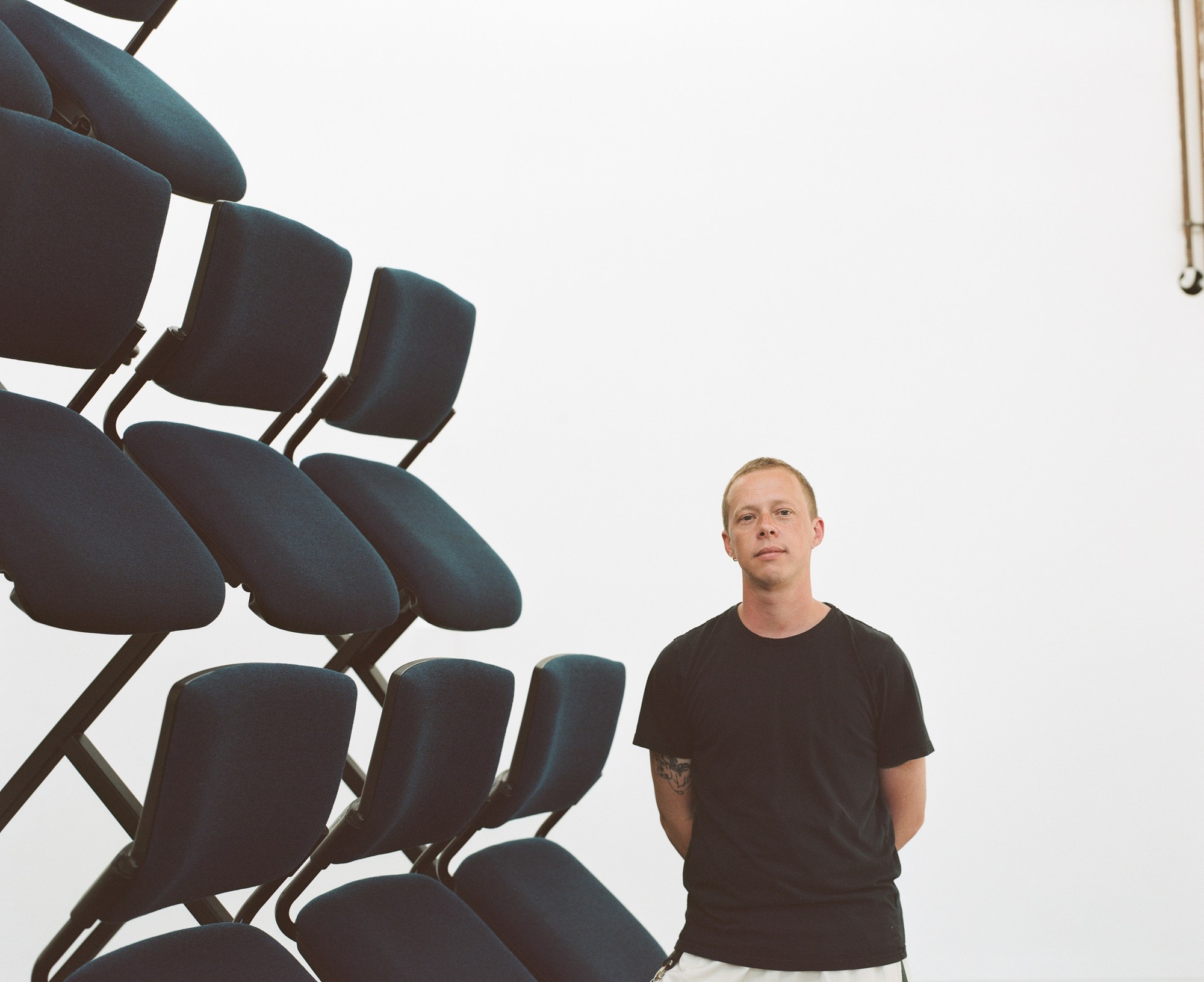 Portrait of a man standing beside stacked folding chairs