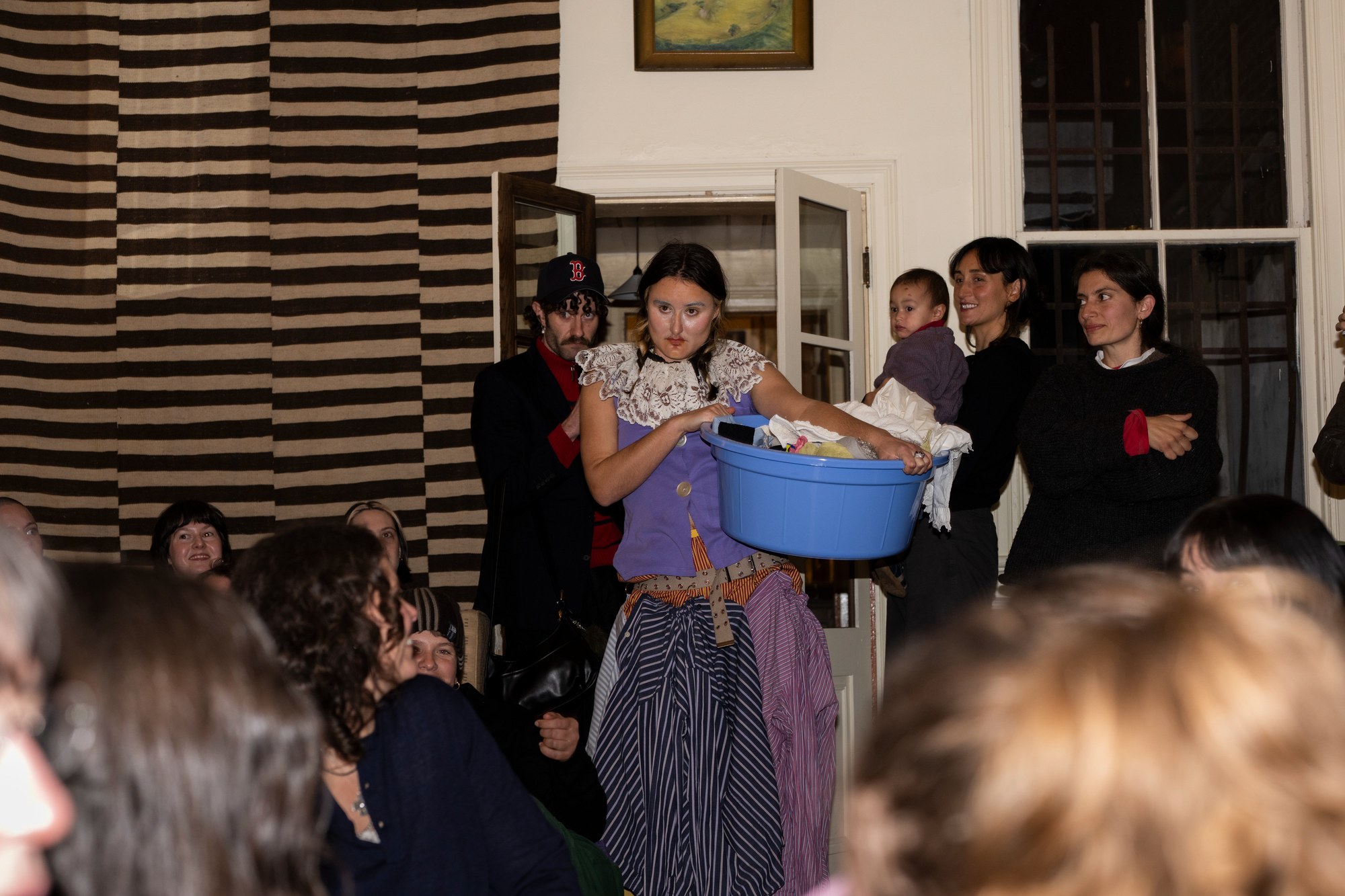 A performer carrying a blue laundry basket through a crowd of onlookers