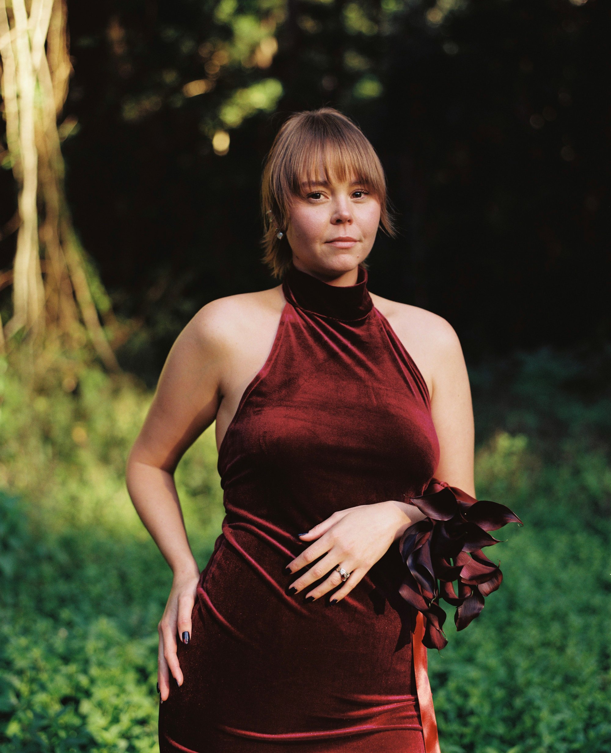 Portrait of a bride in a burgundy velvet dress holding dark flowers